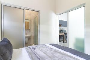 a bedroom with a bed and a bathroom at #AlimamaSpaces Buko's Greenlee Apartment in Sandton +21 photos