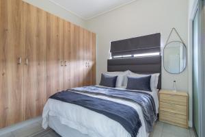 a bedroom with a large bed and wooden cabinets at #AlimamaSpaces Buko's Greenlee Apartment in Sandton