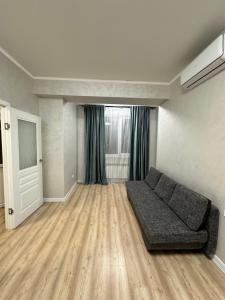 a living room with a couch and a window at Квартира на Торайгырова in Almaty