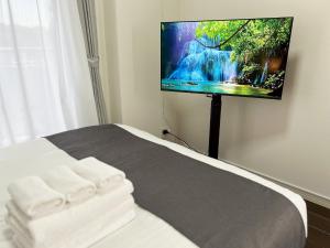 ein Schlafzimmer mit einem Bett und einem Fernseher an der Wand in der Unterkunft Lion Heiwa Odori - Vacation STAY 18061 in Hiroshima