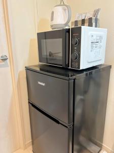 eine Mikrowelle auf einem Kühlschrank in der Unterkunft Lion Heiwa Odori - Vacation STAY 18059 in Hiroshima