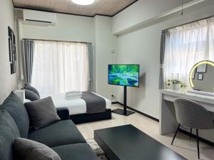 ein Wohnzimmer mit einer Couch und einem Bett und einem Fernseher in der Unterkunft Lion Heiwa Odori - Vacation STAY 17952 in Hiroshima
