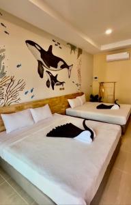 Un dormitorio con dos camas con un mural de delfines en la pared. en De Mer Resort Rayong, en Ban Ao Makham Pom