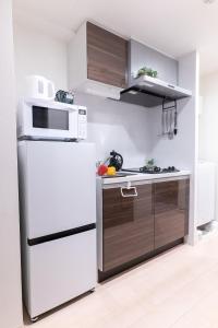 a kitchen with a white refrigerator and a microwave at WOM Condominium Tamatsukuri - Vacation STAY 64193v in Osaka