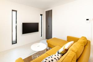 a living room with a yellow couch and a tv at GUMPAKU Maebashi - Vacation STAY 81491v in Maebashi