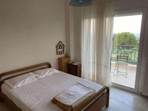 1 dormitorio con 1 cama y puerta a un balcón en Sunnyhomes Livithra, en Leptokarya