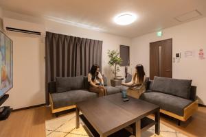 two women are sitting in a living room at Guesthouse Ogaki Kokone C, D - Vacation STAY 72653v in Ogaki