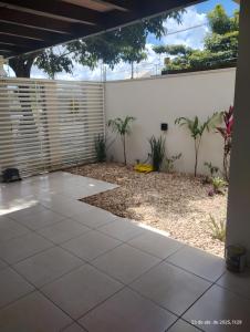 an empty patio with a white wall and plants at Quarto 1 cama de casal com ar estacionamento in Sinop