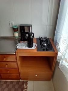 a kitchen counter with a coffee maker on a stove at Quarto 1 cama de casal com ar estacionamento in Sinop +1 photo