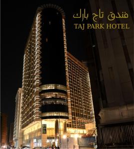 a tall building with a sign on it at night at Taj Park Hotel in Mecca