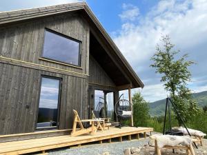 Una cabaña de madera con una mesa y sillas en una terraza. en Cabin at Norefjell ski resort, nice view, en Noresund