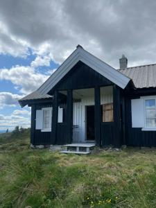 a black and white house in a field at Traditional Mountain Cabin Near Hallingskarvet in Torpo