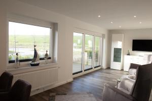 a living room with a window with a couch and a television at Deichhöhe 7 HU in Norddeich