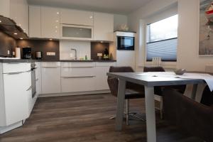 a kitchen with white cabinets and a table with chairs at Deichhöhe 7 HU in Norddeich