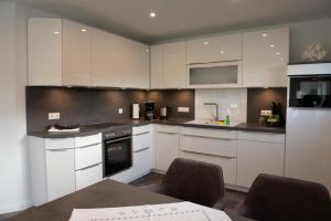 a kitchen with white cabinets and a stove top oven at Deichhöhe 7 HU in Norddeich +4 photos