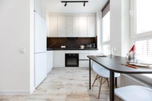 uma cozinha com armários brancos e uma mesa em Nyvky Like Home - Нивки Парк - Студія 40-2 em Kiev