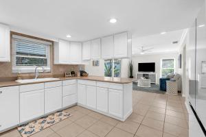 a kitchen with white cabinets and a living room at Helene's Coastal Escape in Sarasota