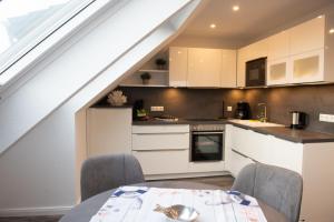 a kitchen with white cabinets and a table with chairs at Deichhöhe 7 HO 1 in Norddeich