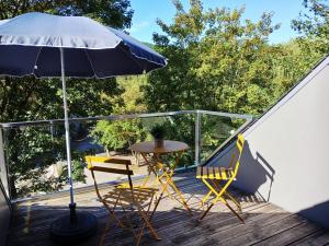 a table and chairs and an umbrella on a deck at Studio "Coeur du Lac" in Vielsalm