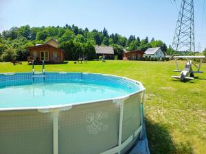 a small pool in a field with a playground at Domek nad Olszanka in Olszanica