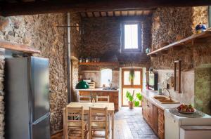 a kitchen with stone walls and a refrigerator at Can Gandaia in Viladamat