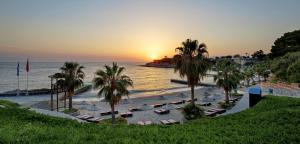 a beach with umbrellas and palm trees at sunset at Pine Bay Holiday Resort in Kusadası +73 photos