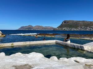 a woman sitting in a hot tub next to the ocean at Stylish beachside Gem in Fish Hoek in Fish Hoek