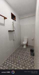 a bathroom with a toilet and a tile floor at Teman Homestay in Kuta Lombok