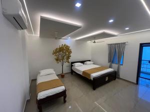 ein Schlafzimmer mit 2 Betten und einer Pflanze darin in der Unterkunft Sakthi Guest House in Tiruvannāmalai