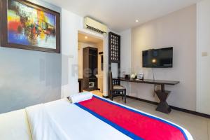 a bedroom with a bed and a desk and a tv at Ozz Hotel Kuta Bali manage by Ozz Group in Kuta
