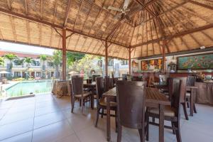 a restaurant with tables and chairs and a swimming pool at Ozz Hotel Kuta Bali manage by Ozz Group in Kuta