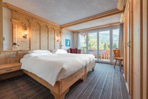 a bedroom with a large bed and a large window at ERMITAGE Wellness- & Spa-Hotel in Gstaad +144 photos