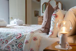 une bougie sur une table à côté d'un lit dans l'établissement Heritage Swiss Cottage, à Matlock Bank