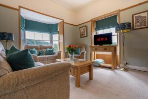 un salon avec un canapé et une télévision dans l'établissement Heritage Swiss Cottage, à Matlock Bank