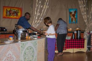 a group of people standing around a table preparing food at Masai Mara Explore Camp in Narok