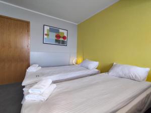 two twin beds in a room with yellow walls at Hotel Jabłoński in Dorotowo