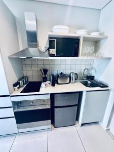 a small kitchen with a sink and a microwave at Urban Elephant, The Rose in Cape Town