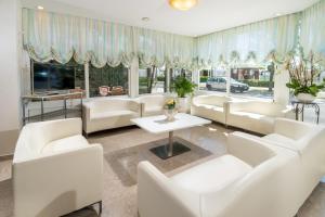a living room with white couches and a tv at Hotel Alba Serena in Misano Adriatico