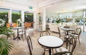 a restaurant with tables and chairs in a room at Hotel Alba Serena in Misano Adriatico