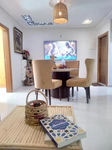 Una sala de estar con una mesa y sillas y un televisor. en Riad of Serenity Briech, en Asilah
