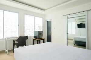 a white bedroom with a bed and a chair at David Houses Nusa Dua Beach Bali RedPartner in Nusa Dua