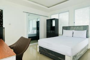a bedroom with a large bed and a chair at David Houses Nusa Dua Beach Bali RedPartner in Nusa Dua