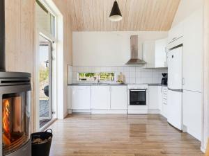 a kitchen with white cabinets and a fireplace at Holiday Home Skogstorp by Interhome in Holmsjö