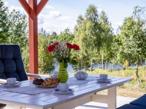 a table with red roses in a vase on it at Holiday Home Skogstorp by Interhome in Holmsjö