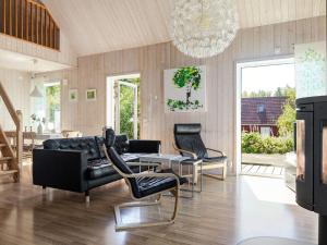 a living room with black leather furniture and a chandelier at Holiday Home Skogstorp by Interhome in Holmsjö +23 photos