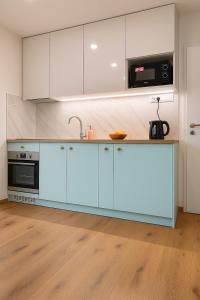 a kitchen with blue cabinets and a microwave at Mini Apartman - Parking free - 5 min center in Nitra