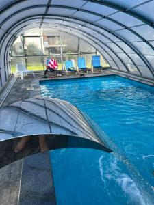 une piscine intérieure avec des chaises et un parasol dans l'établissement Morska Ballada apartament 43m2 przy morzu, garaż, basen, sauny, à Jastrzębia Góra