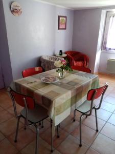 a dining room table with red chairs and a table with flowers on it at Les claux -185 rue des Claux in Saint-Romain-dʼAy
