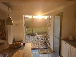 eine Küche mit einer Tür, die auf eine Terrasse mit Sonnenuntergang führt in der Unterkunft Strandhuset in Agger + 38 Fotos