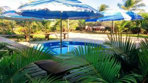 two blue umbrellas sitting next to a swimming pool at Araticum Praia Hotel in Santo André